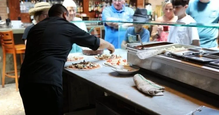 A tour group watching a pizzaiolo at work